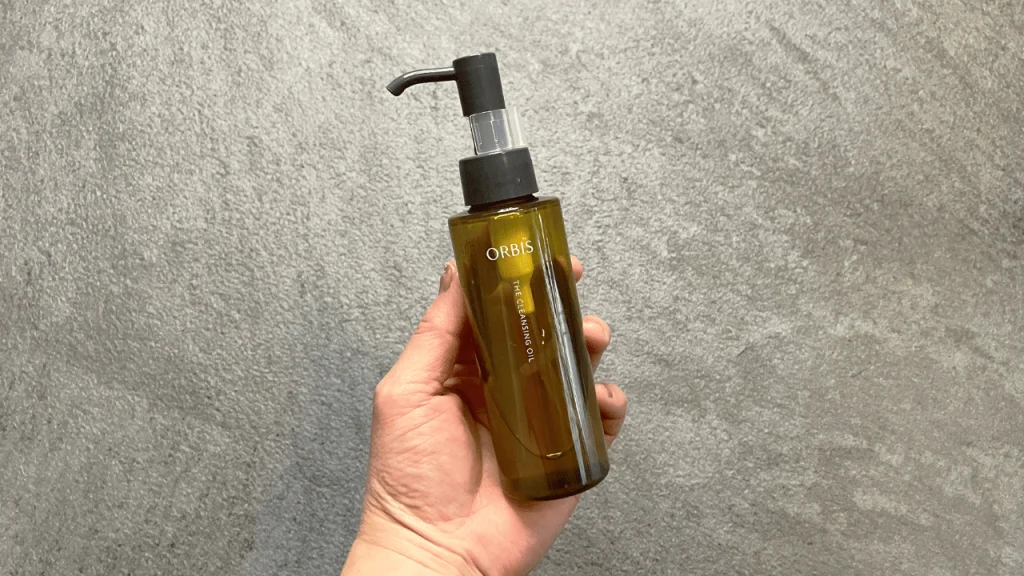 オルビス ザ クレンジング オイルのボトルを手に持っている