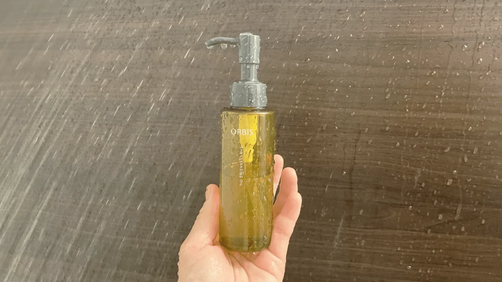 オルビス ザ クレンジング オイルのボトルを手に持っている